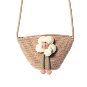 Detail of khaki woven crossbody bag featuring a large cream 3D fabric flower and zipper