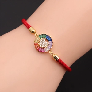 Detail of red woven bracelet featuring a colorful zircon star and heart charm on wrist