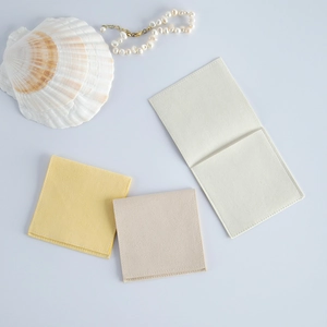Flat lay of velvet jewelry pouches in yellow and beige with decorative shell and pearls