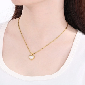 Close-up of gold heart shell pendant on twisted chain necklace worn by a model