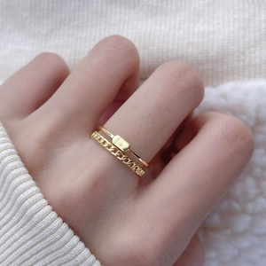 Close-up of minimalist gold-plated double-layer chain and plaque rings on a finger