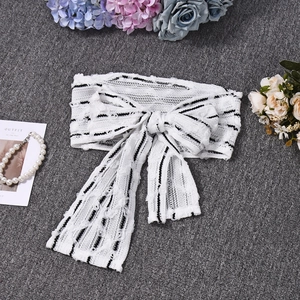 Detailed view of white knitted headband with black stripes and elegant bow design