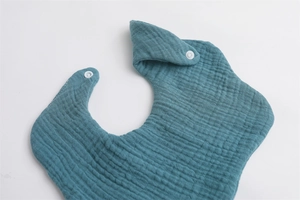 Close-up of green 6-layer muslin cotton baby bib showing soft texture and snap button