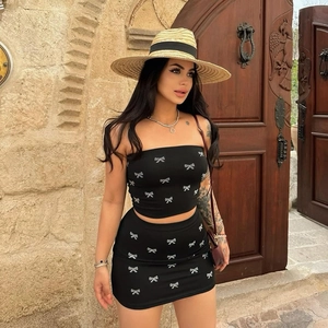 Detail of black two-piece set with silver bow patterns featuring tube top and mini skirt