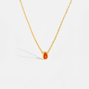 Macro shot of gold S925 sterling silver chain with a pear-shaped red teardrop pendant