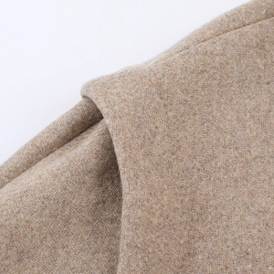 Makro-Detailansicht der hellbeige Wollmischung und Textur des eleganten Wollmantels