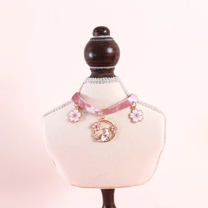 Detail of pink velvet pet collar with cherry blossom and cat pendants on mannequin
