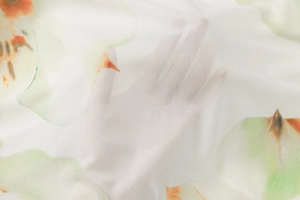 Close-up of white mesh fabric featuring green and orange floral print details