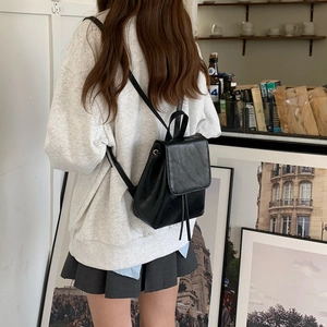 Mini zaino in pelle nera con coulisse mostrato in un ambiente cafe lifestyle