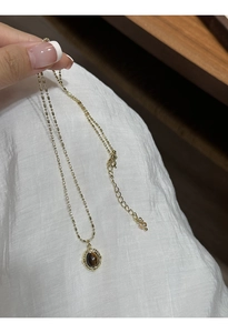 Detail of vintage gold-plated bead chain with tiger eye stone oval pendant on model
