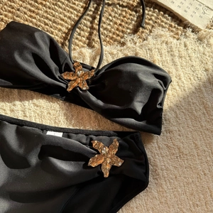 Detailansicht der goldenen Seestern-Metallschnalle an einem schwarzen Bikini