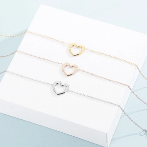 Close-up of three hollow heart bracelets in gold, rose gold, and silver stainless steel