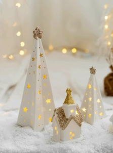 Close-up of glowing ceramic star Christmas tree and church with gold glitter accents