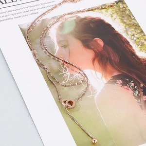 Close-up of rose gold double-layer necklace with interlocking rings and fringe pendant