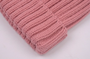 Close-up of pink knit beanie showing thick ribbed texture and folded cuff detail