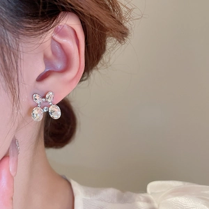 Detail view of silver earrings with oval crystals in a floral design worn by a model