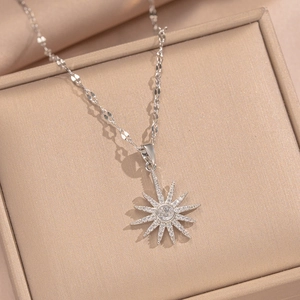 Silver starburst pendant necklace with central diamond setting on champagne silk background
