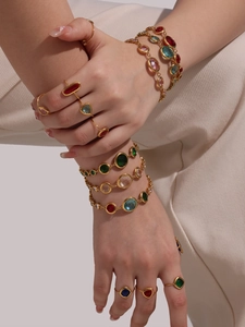 Detailed view of vintage gold bracelets and rings with colorful gemstones on a model
