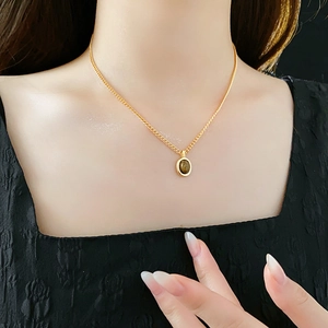 Détail d'un collier vintage doré avec pendentif oeil de tigre porté sur modèle