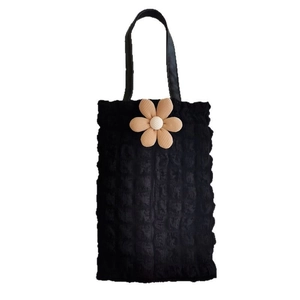 Detail of black bubble textured tote bag with a 3D beige flower on white background