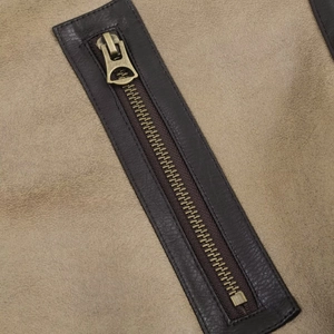 Detailed close-up of retro bronze metal zipper on a beige double-sided jacket