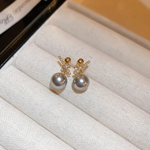Elegant gold knot earrings with grey pearls and cubic zirconia on velvet display
