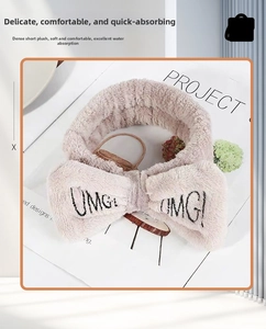 Detailed close-up of pink coral fleece headband with OMG embroidery and bow for skincare