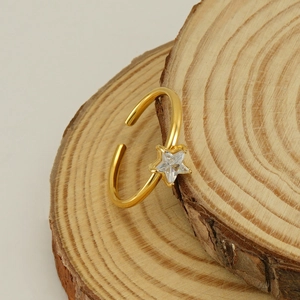 Bague ouverte dorée avec zircon en forme d'étoile et cristal scintillant sur bois