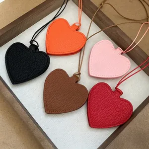 Litchi texture leather heart pendants in five colors arranged on a wooden tray