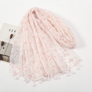 Close-up of light pink floral print scarf with soft white tassels and linen feel
