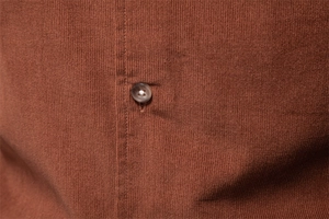 Macro della trama in velluto a coste sottili e bottone in resina di una camicia