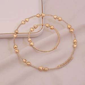 Set di gioielli dorati con collana e bracciale a forma di cuore decorati con strass luminosi