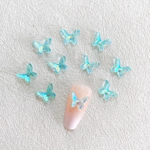 Light blue 3D aurora resin butterfly nail charms on a textured white background