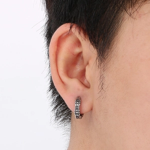 Close-up of retro silver stainless steel hoop earring with embossed vintage textures