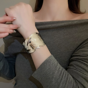 Detail of silver irregular metal cuff bracelet with leaf texture on a model's wrist