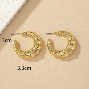 Detailed close-up of golden twisted hoop earrings with 3cm by 3.3cm dimensions