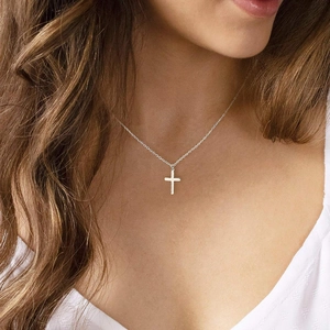 Close-up of a minimalist silver stainless steel cross pendant necklace on a model
