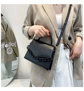 Close-up of black leather crossbody bag with a chunky chain and removable shoulder strap