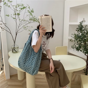 Blue floral canvas tote bag held by a model in a minimalist modern interior scene