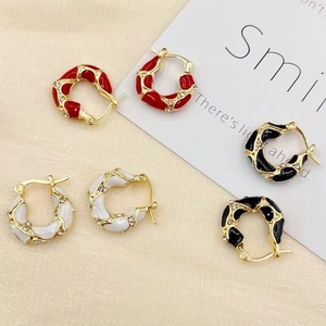 Detailed close-up of colorful enamel twist hoop earrings in red, white and black colors