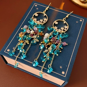 Close-up of vintage gold star tassel earrings with blue and purple faceted crystal beads