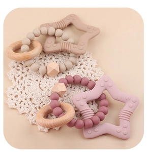 Detailed view of pink and beige silicone star teethers with wooden rings on lace