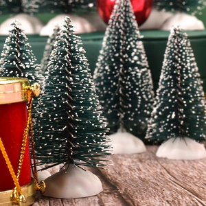 Detailed close-up of mini snow-flocked Christmas trees and festive drum ornaments