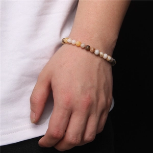 Natural 6mm stone bead bracelet featuring mixed neutral earth tones on a model's wrist