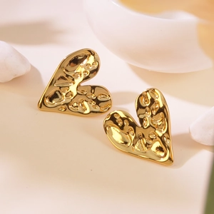 Detail of gold heart earrings with unique hammered texture on an elegant background
