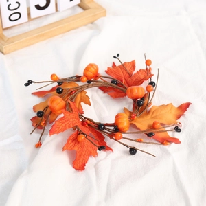 Detailed view of Halloween pumpkin candle ring with maple leaves on white fabric background