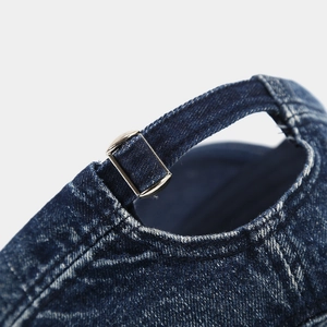 Detail of adjustable metal buckle on distressed blue denim cap with washed texture