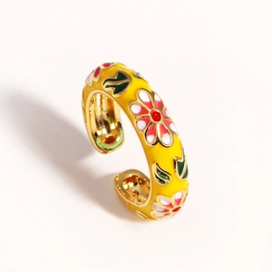 Detail of golden adjustable ring featuring yellow enamel and red floral patterns