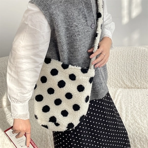 Detailed view of the soft faux shearling bucket bag featuring bold black polka dots