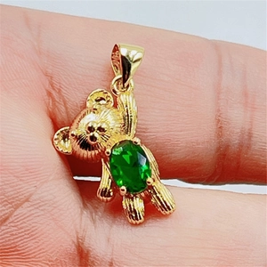 Pendentif ours doré avec zircon vert, tenu en main pour montrer la taille du produit